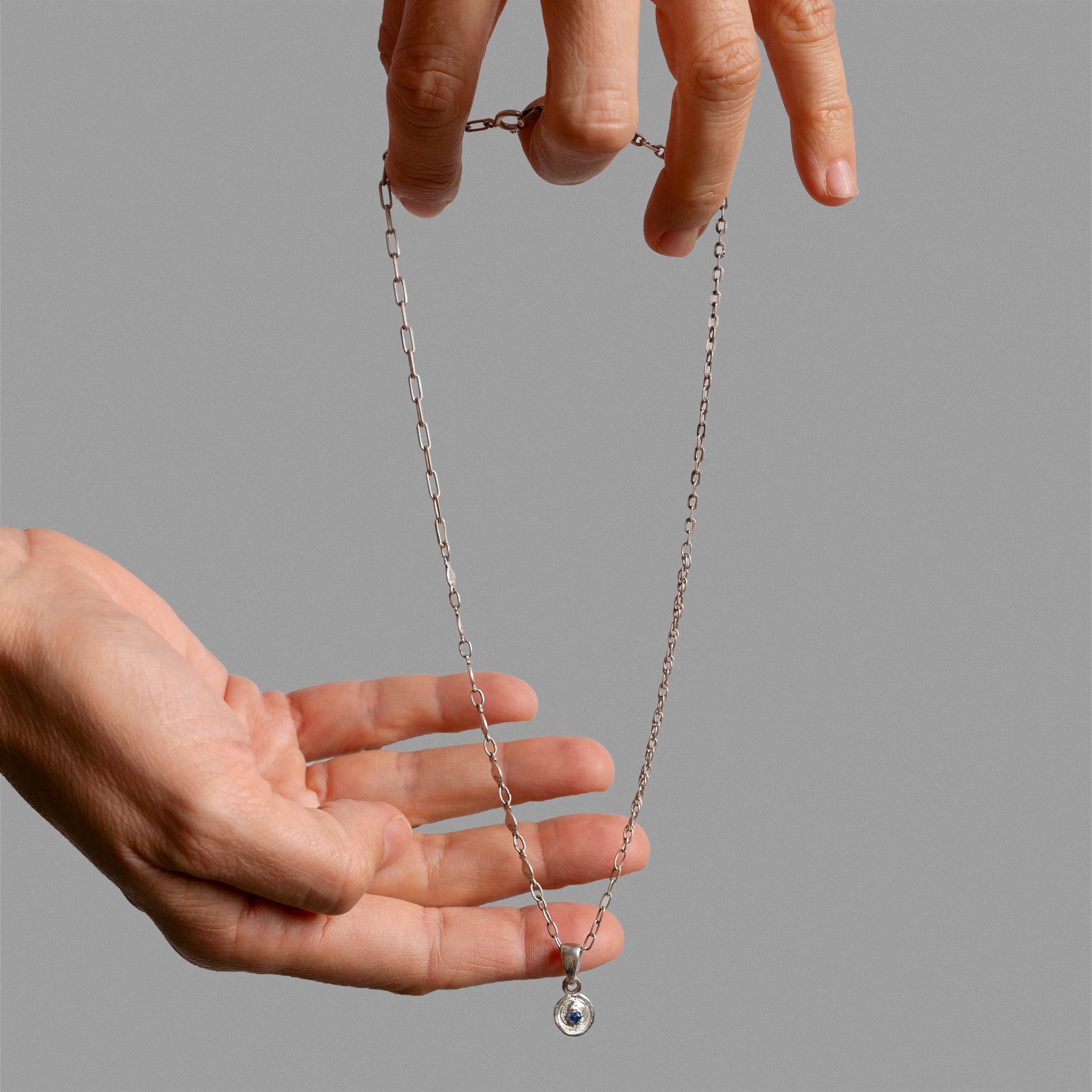 Broken chain pieces with found medal and sapphire.